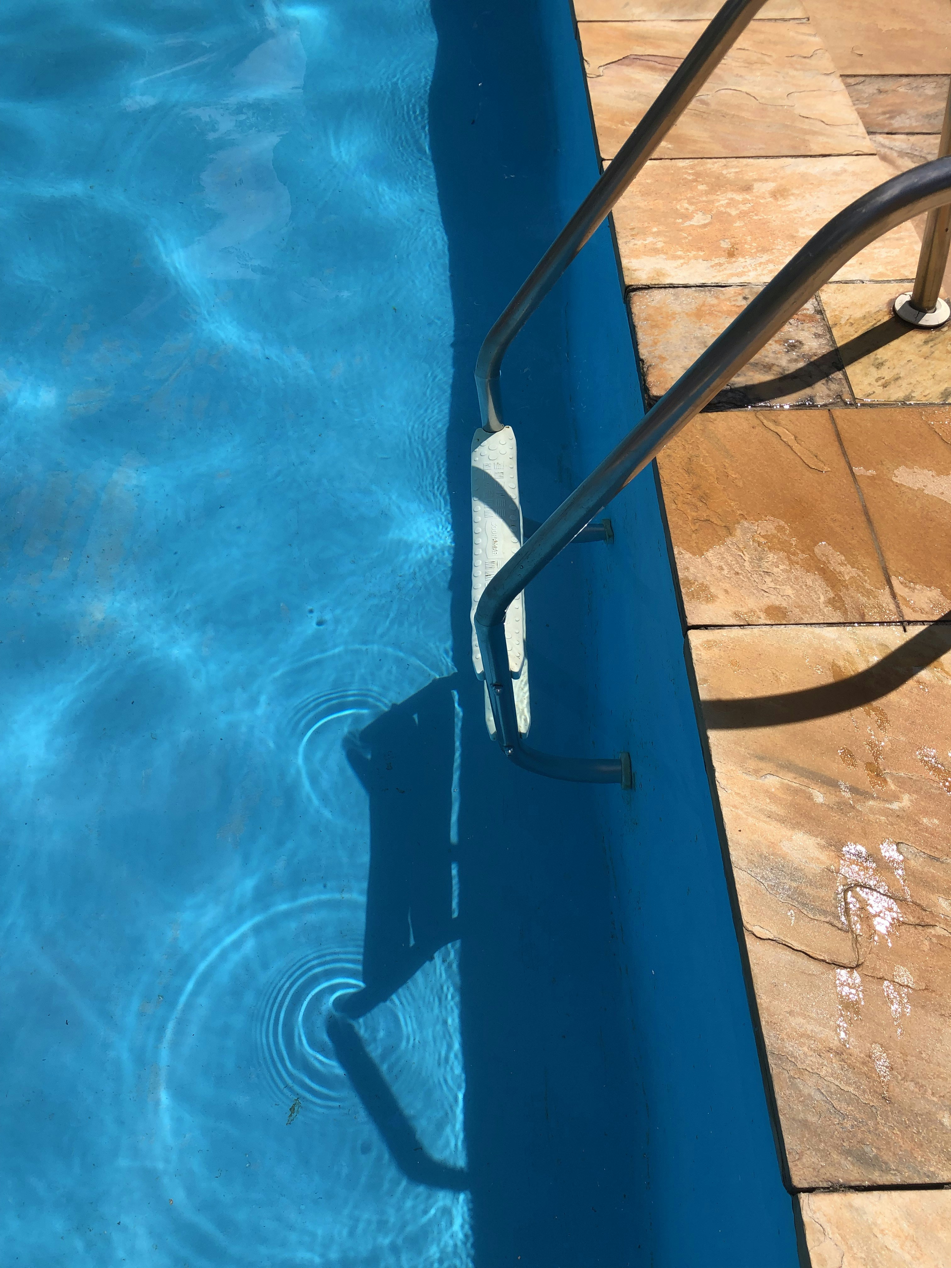 a blue swimming pool with a metal hand rail