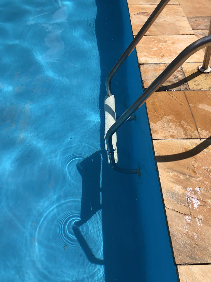 Clean blue residential pool with a stainless steel hand rail