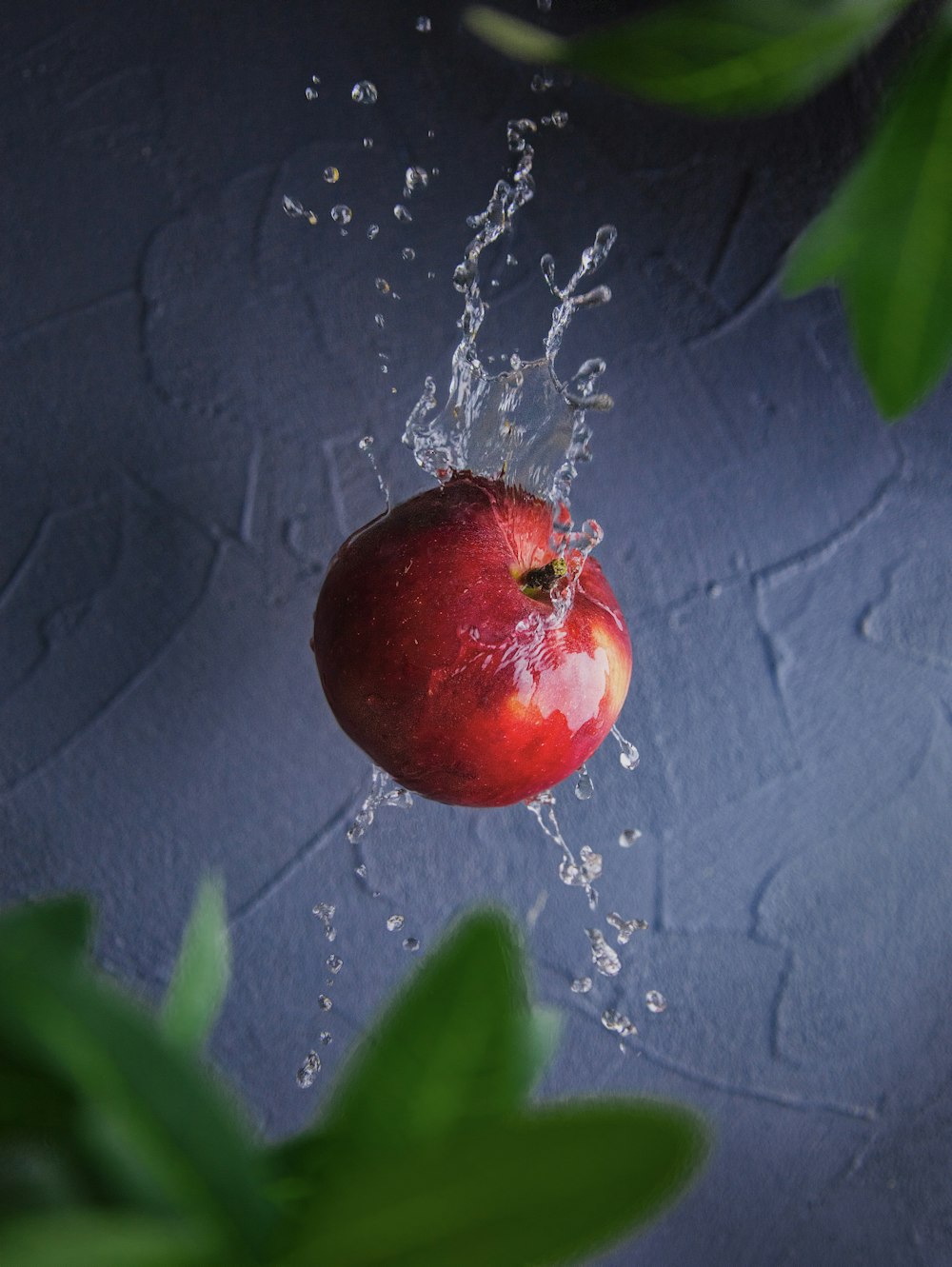 a red apple is being splashed with water