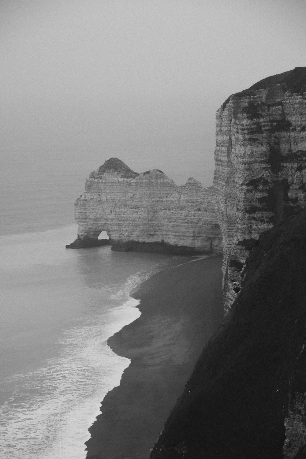 a black and white photo of the ocean and cliffs