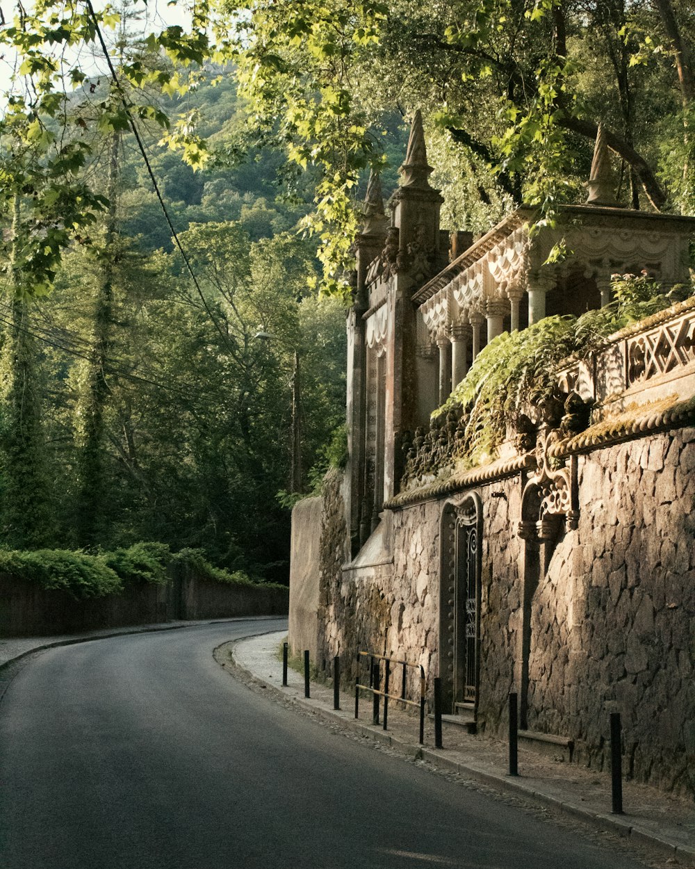 a street with a stone building and trees