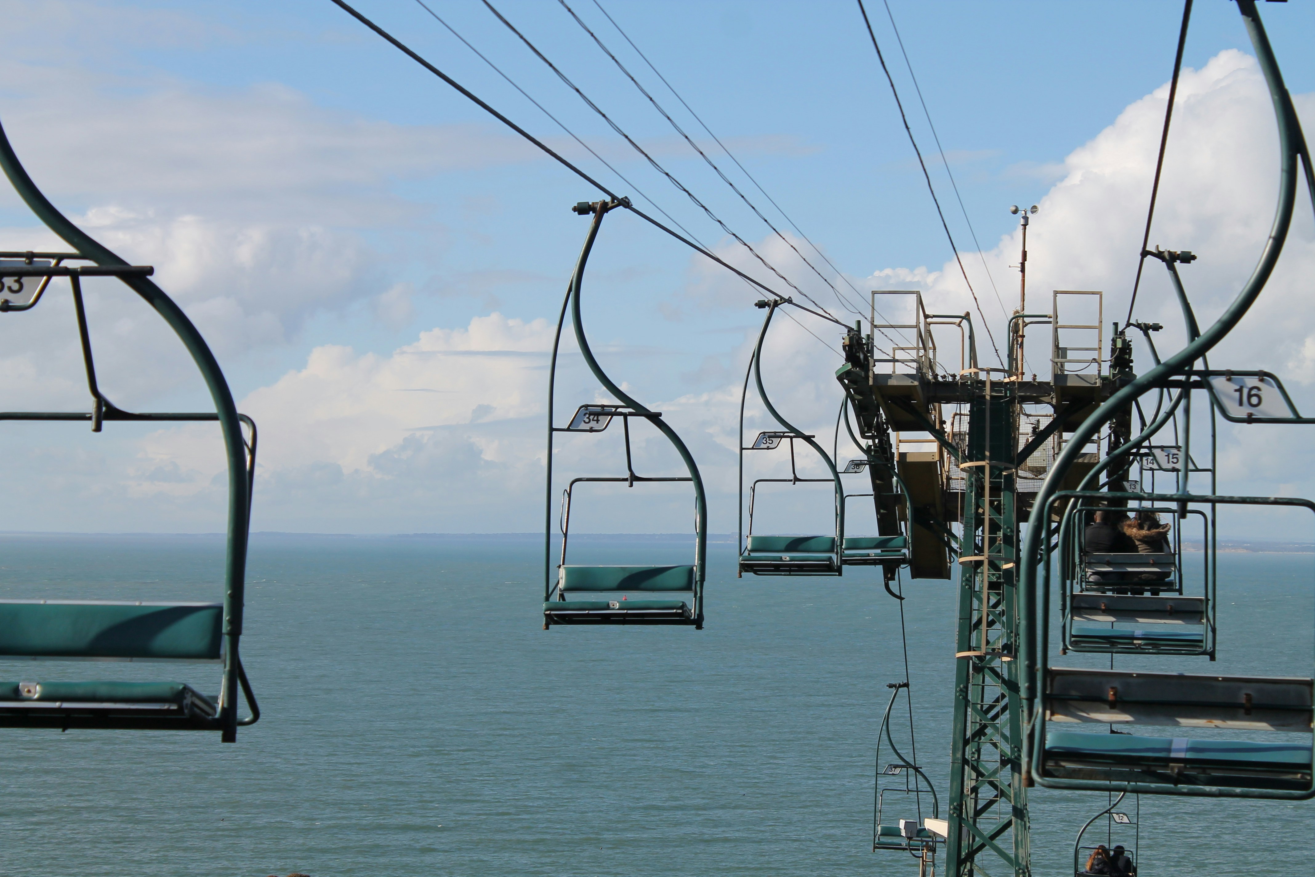 a group of people riding a ski lift over the ocean