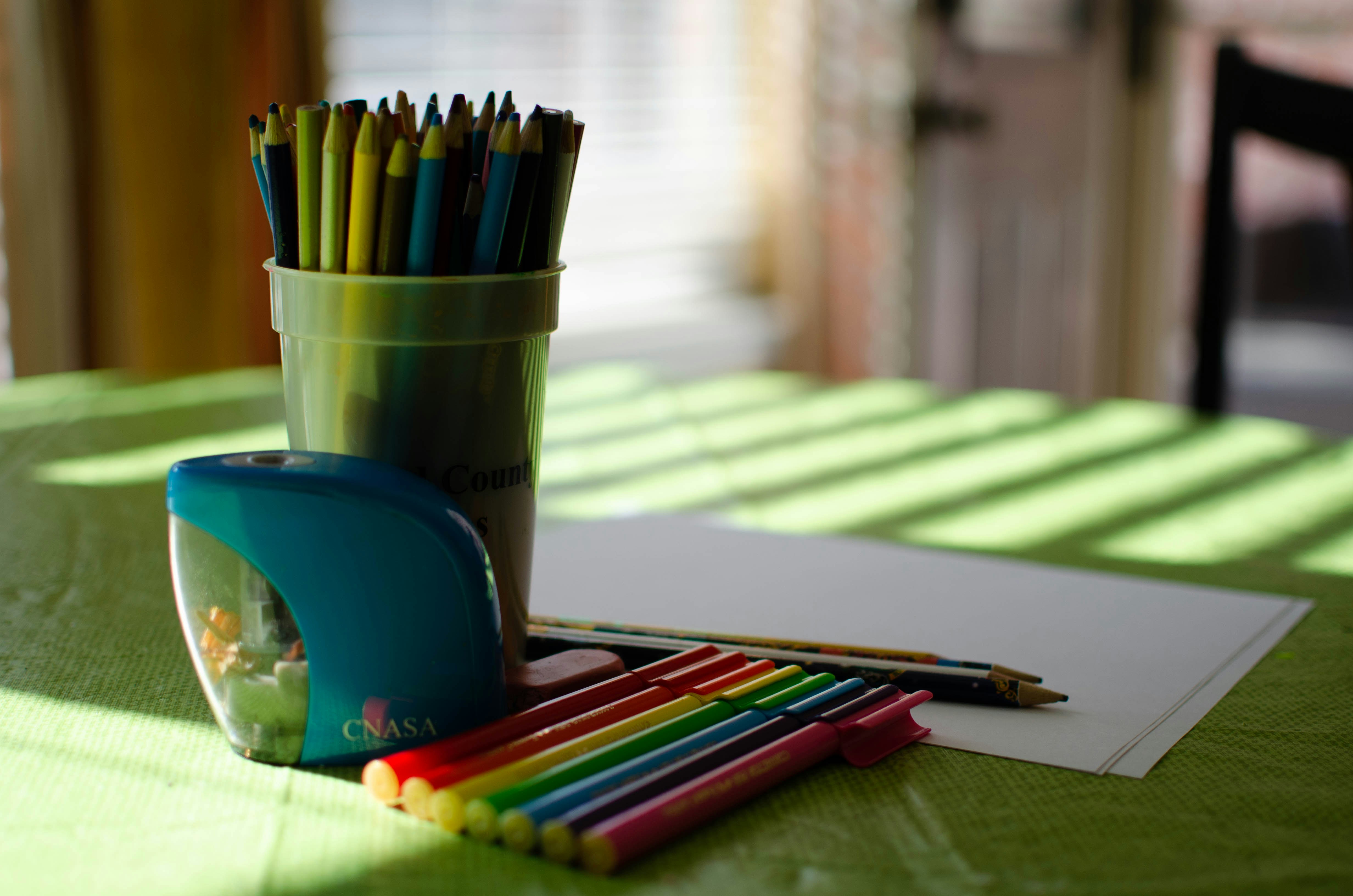 a cup of colored pencils sitting on top of a table