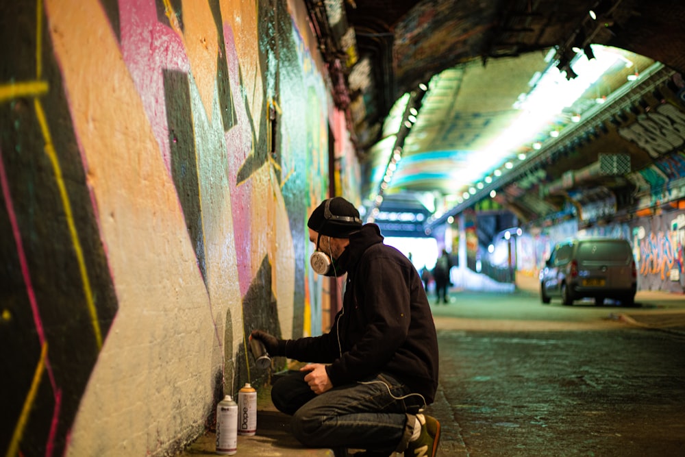 a man sitting on the ground painting a wall