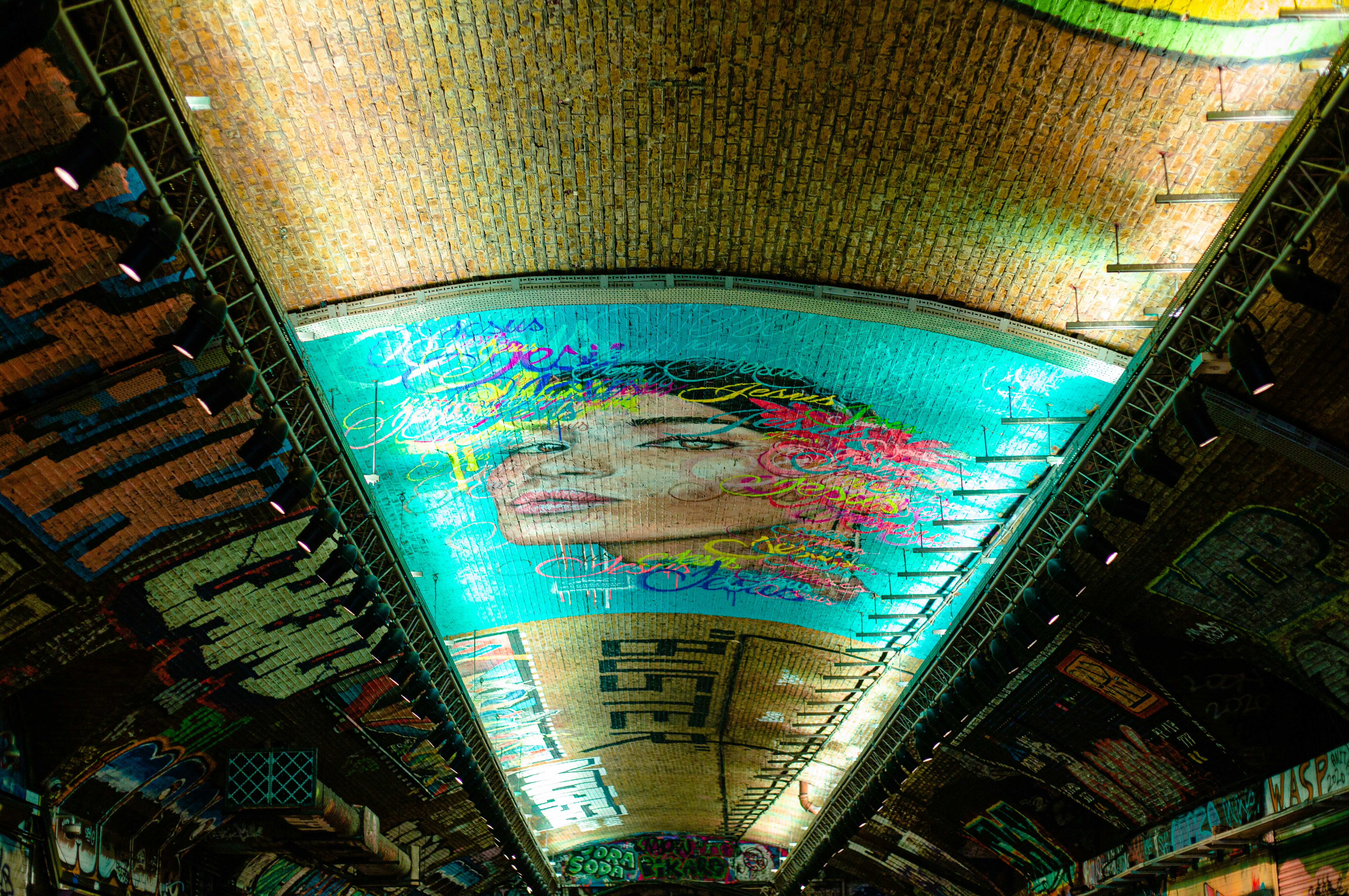 a subway station with a mural of a woman's face on the ceiling