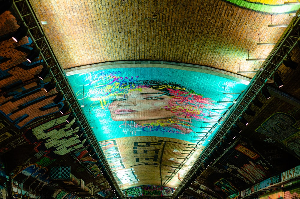 a subway station with a mural of a woman's face on the ceiling
