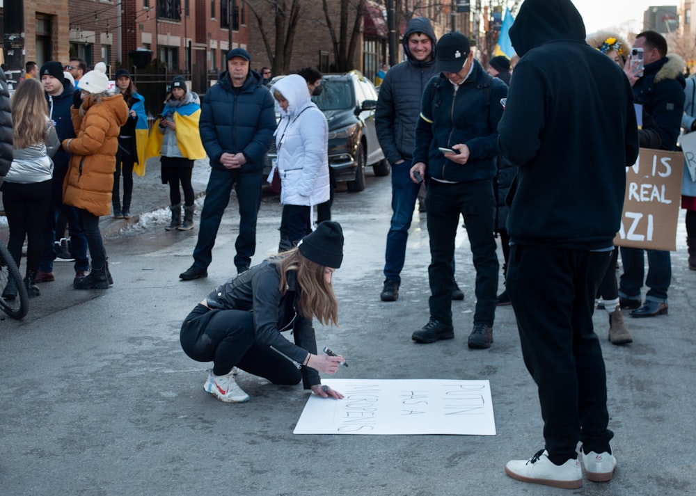 a group of people standing around a woman writing on a piece of paper