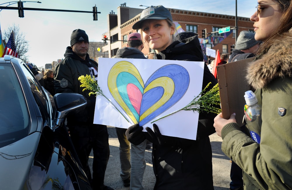 a woman holding a sign with a heart painted on it