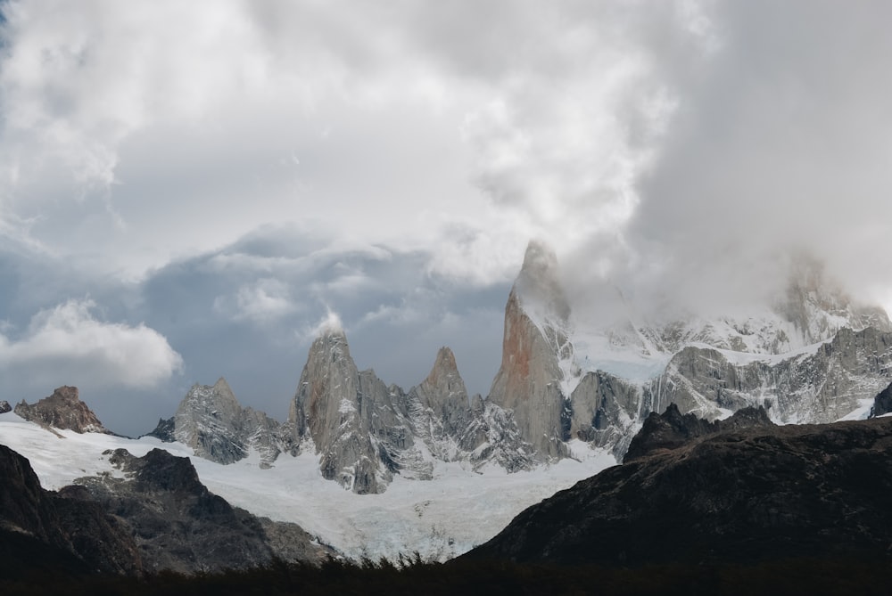 a snow covered mountain range under a cloudy sky