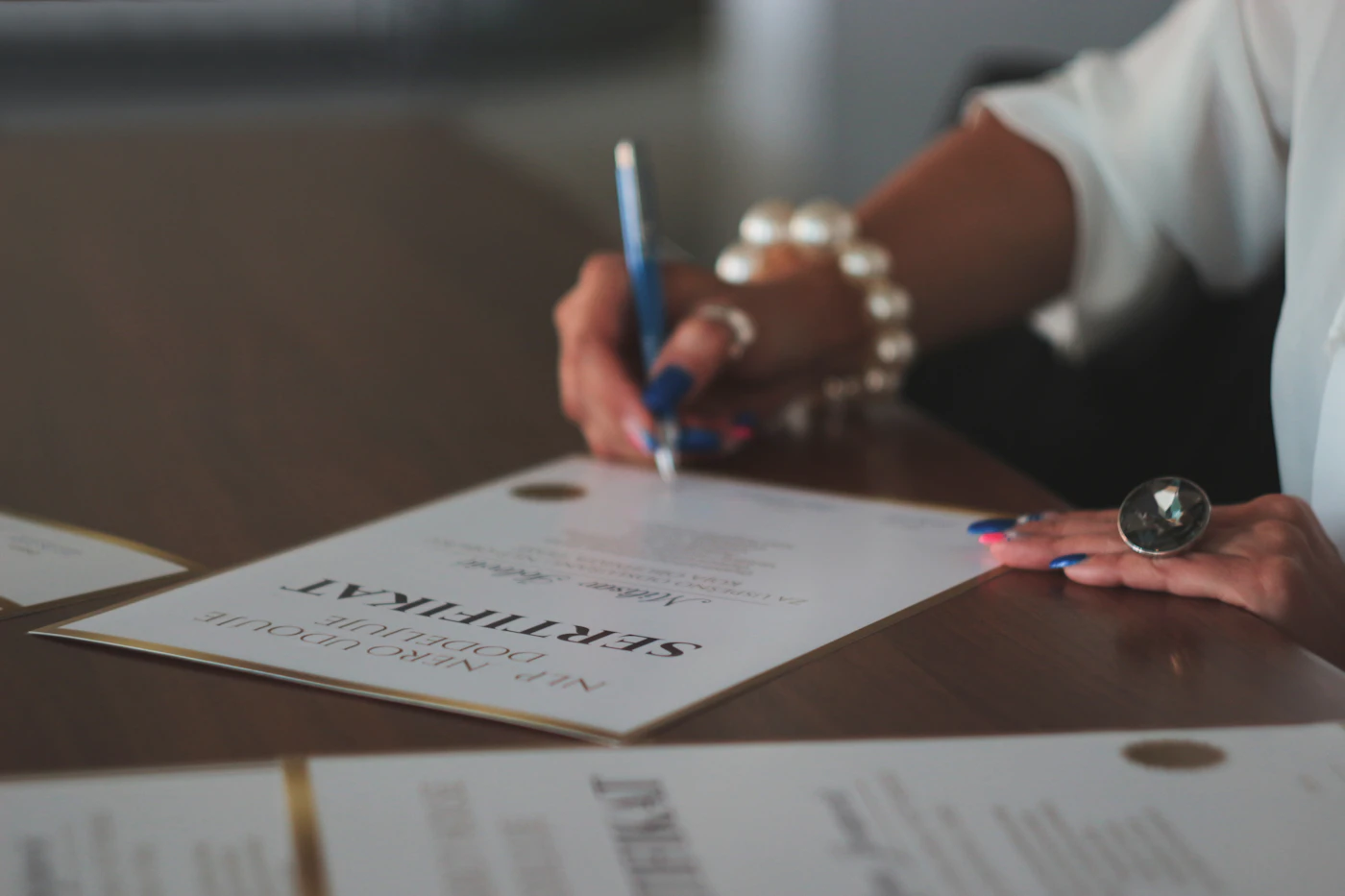 Person signing and receiving a printed teaching certificate at a desk