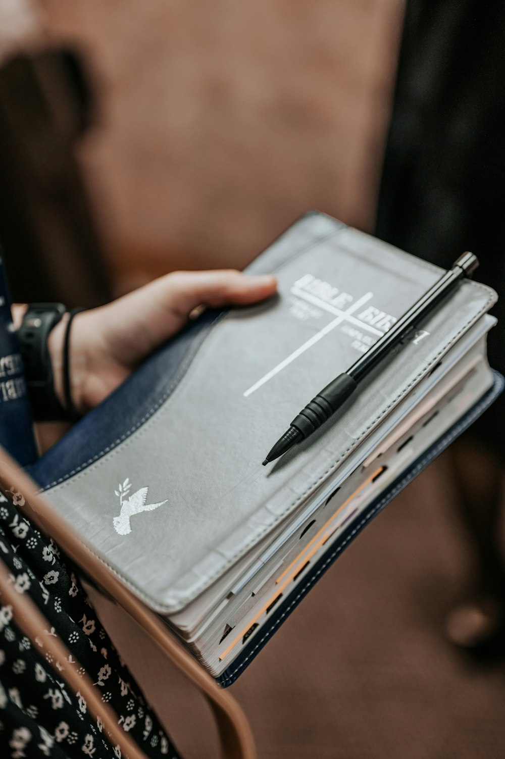 a person holding a notebook with a pen on top of it