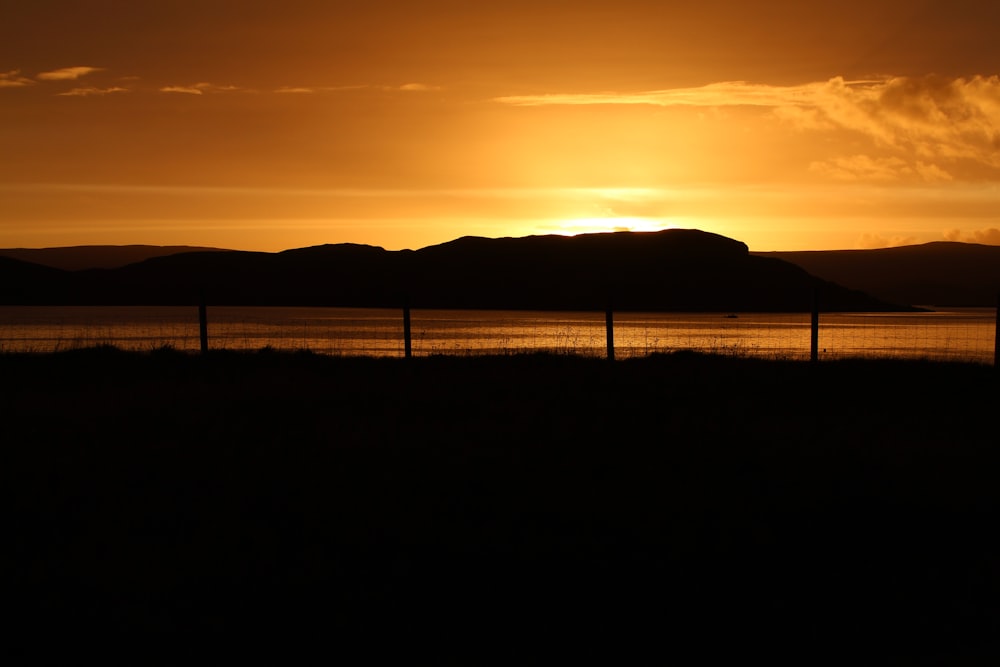 the sun is setting over a lake with mountains in the background