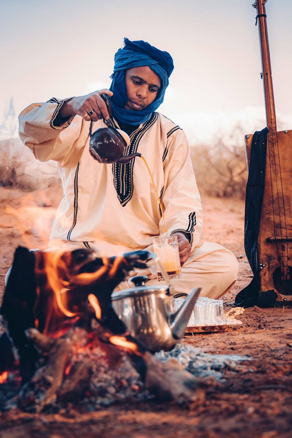 a man sitting in front of a campfire cooking food
