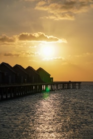 A serene overwater bungalow at sunset in Tahiti, glowing warmly over turquoise waters.