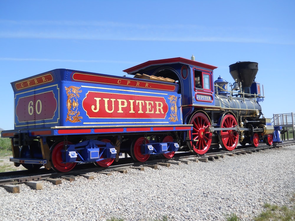 a blue and red train traveling down train tracks