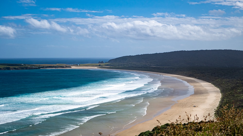 a view of a sandy beach with waves coming in from the ocean