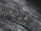 Wooden letters spelling out 'peace' are positioned on a textured, weathered wooden surface. The letters stand out with a light, warm color against the darker, grayish tones of the wood.
