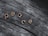 Wooden letters spelling out 'peace' are positioned on a textured, weathered wooden surface. The letters stand out with a light, warm color against the darker, grayish tones of the wood.