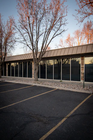A quiet small commercial plaza at dawn with freshly cleaned parking lot and trimmed landscaping.