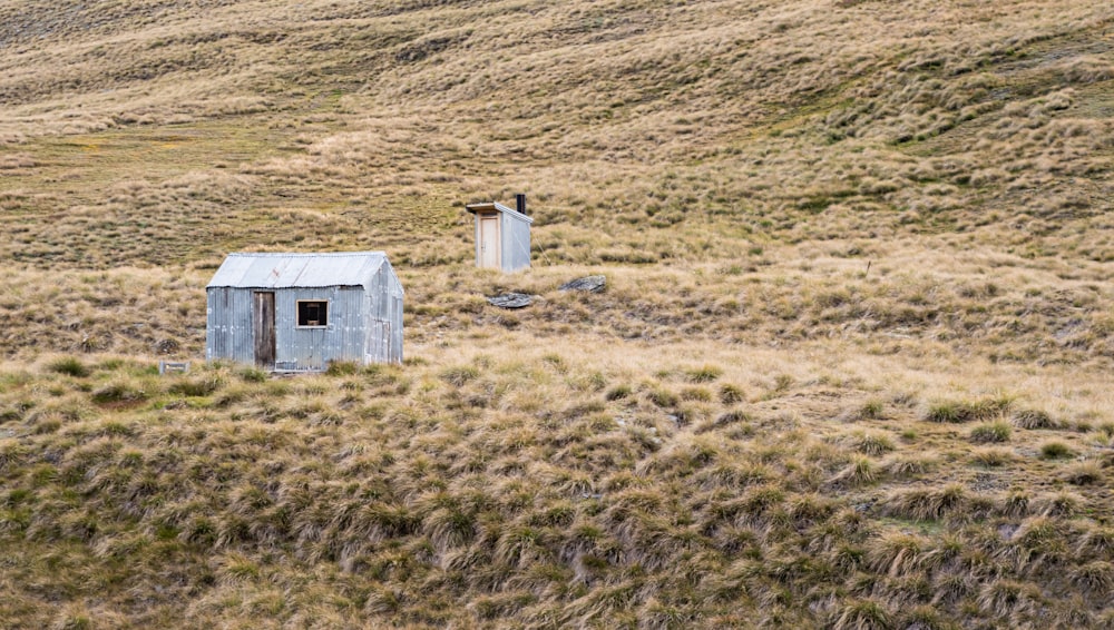 a couple of small buildings sitting in the middle of a field