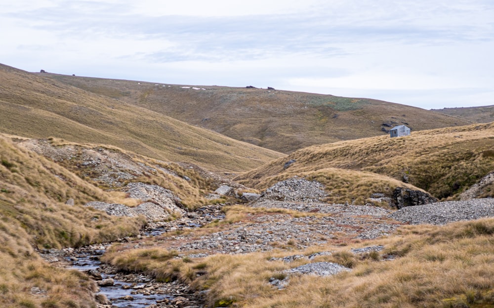 a stream running through a dry grass covered hillside