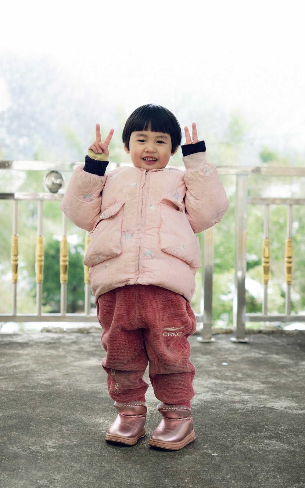 a little girl in a pink jacket and pink pants