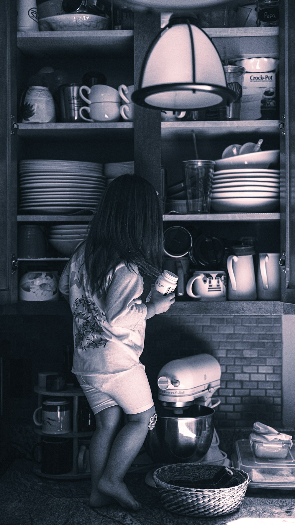 a little girl standing in front of a shelf filled with dishes