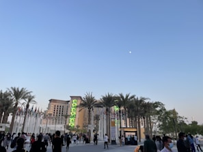 An outdoor scene showing a banner for a UAE job opportunity event with attendees walking by.