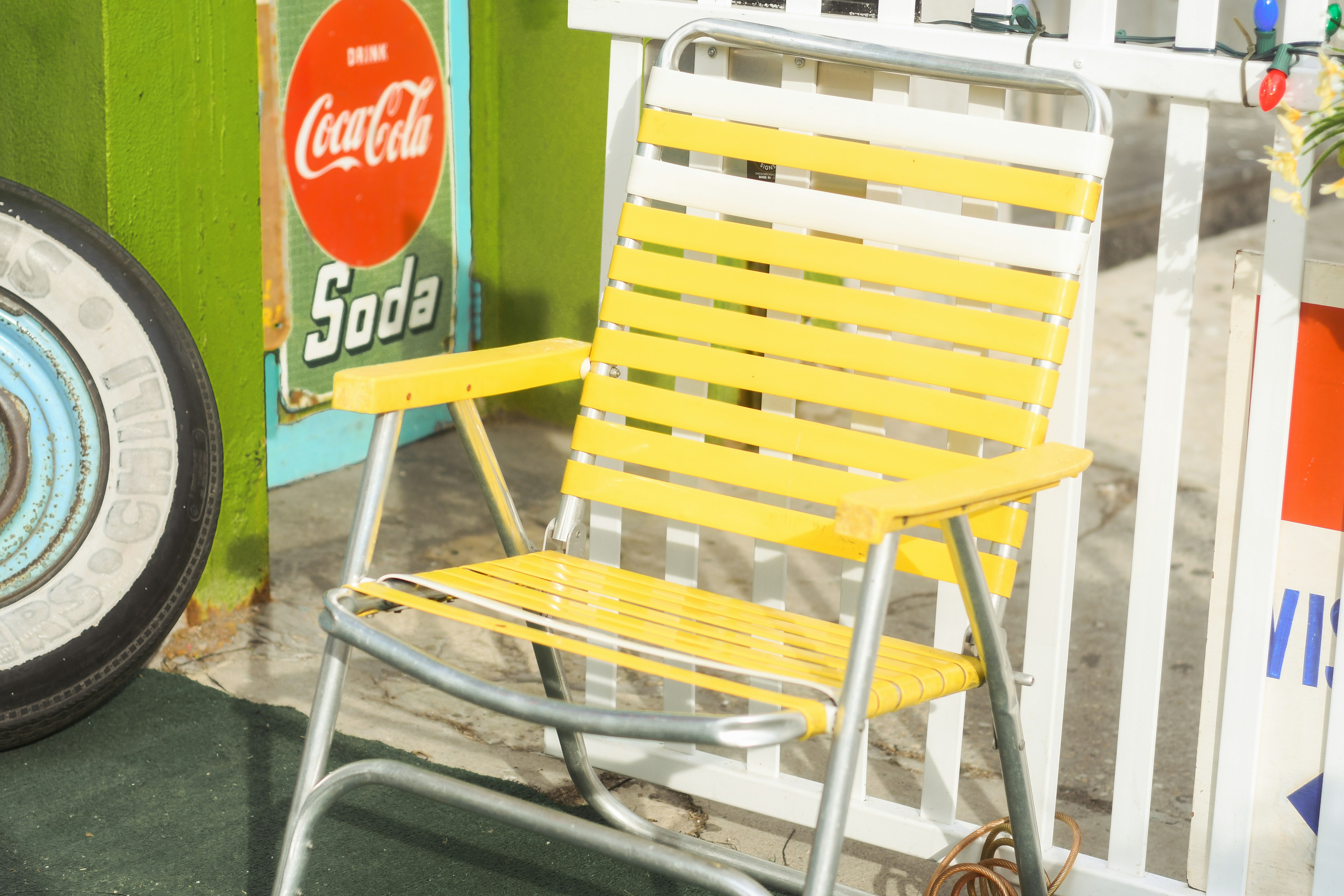 Foto zum Thema Ein gelber Liegestuhl neben einem CocaColaSchild