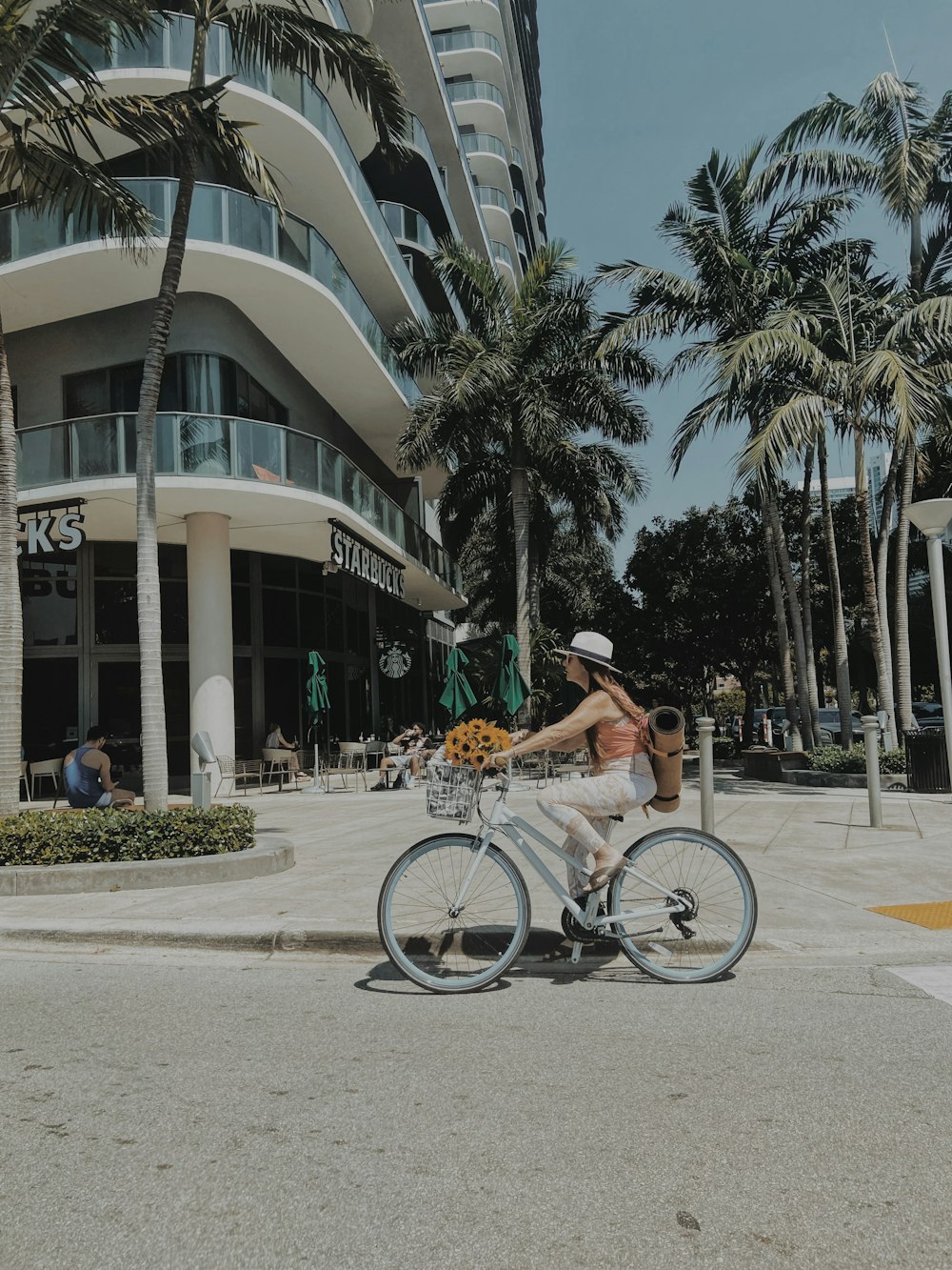 a man riding a bike down a street next to palm trees