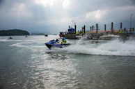 Children watching excitedly from the shore as jet skis zoom past with bursts of spray.