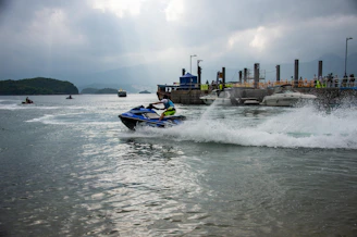 Children watching excitedly from the shore as jet skis zoom past with bursts of spray.