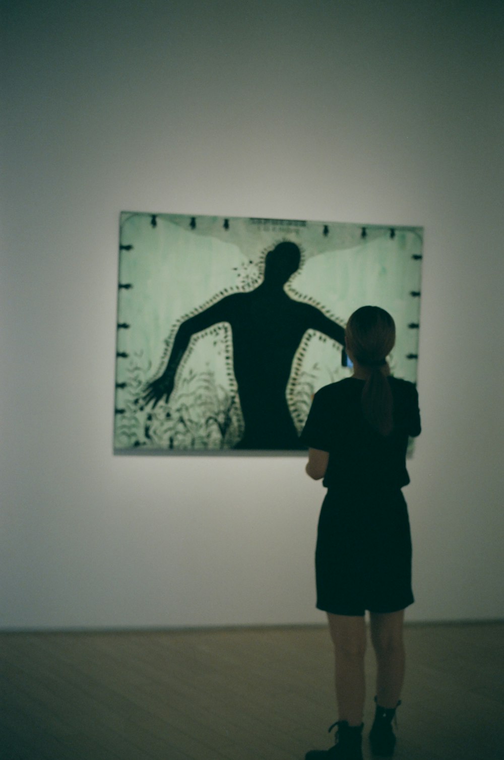 a woman standing in front of a painting on a wall