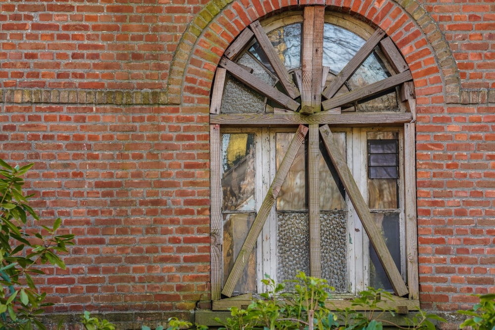 a window with a wooden wheel on the side of a brick building