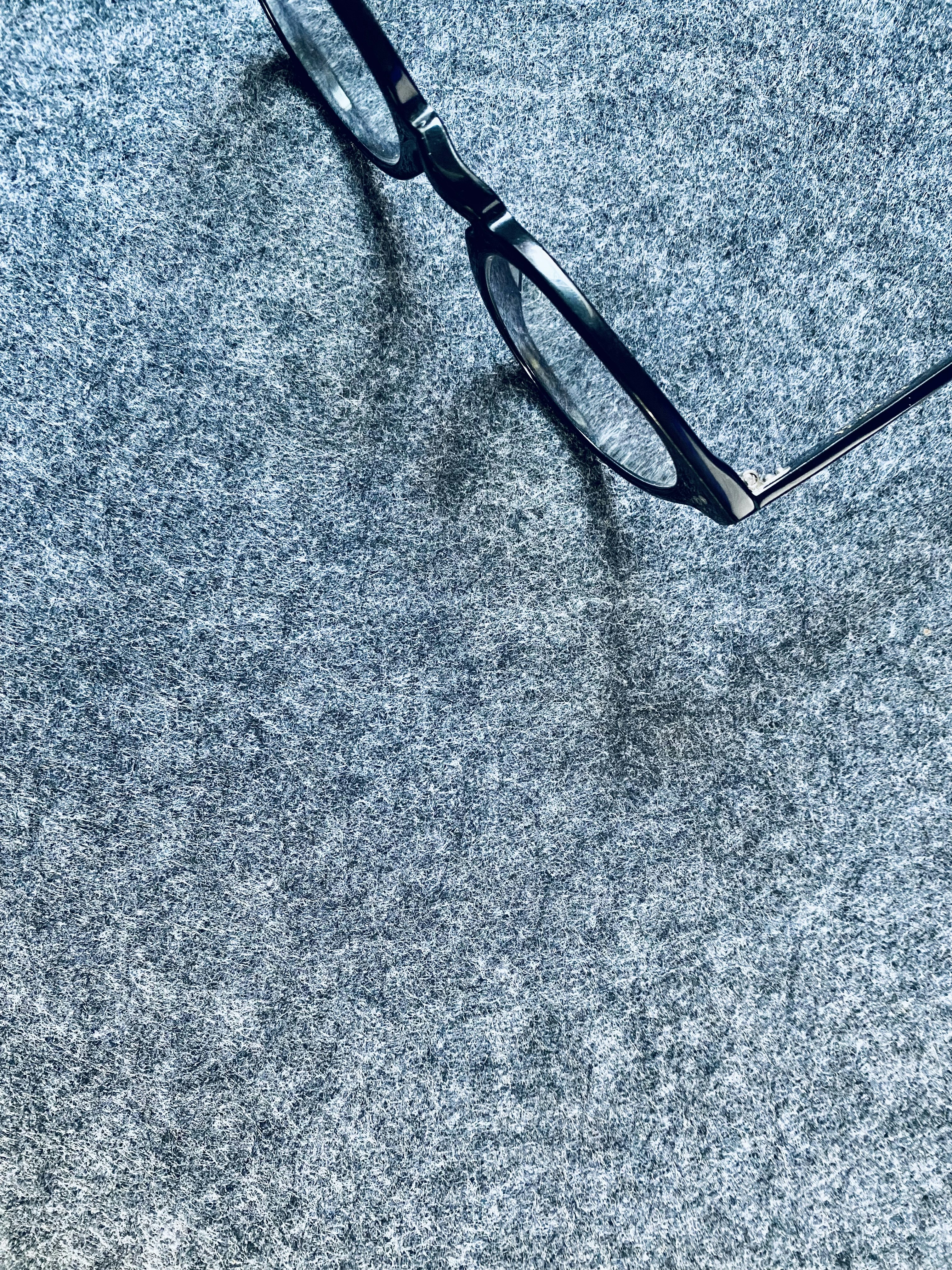 a pair of glasses laying on top of a gray carpet