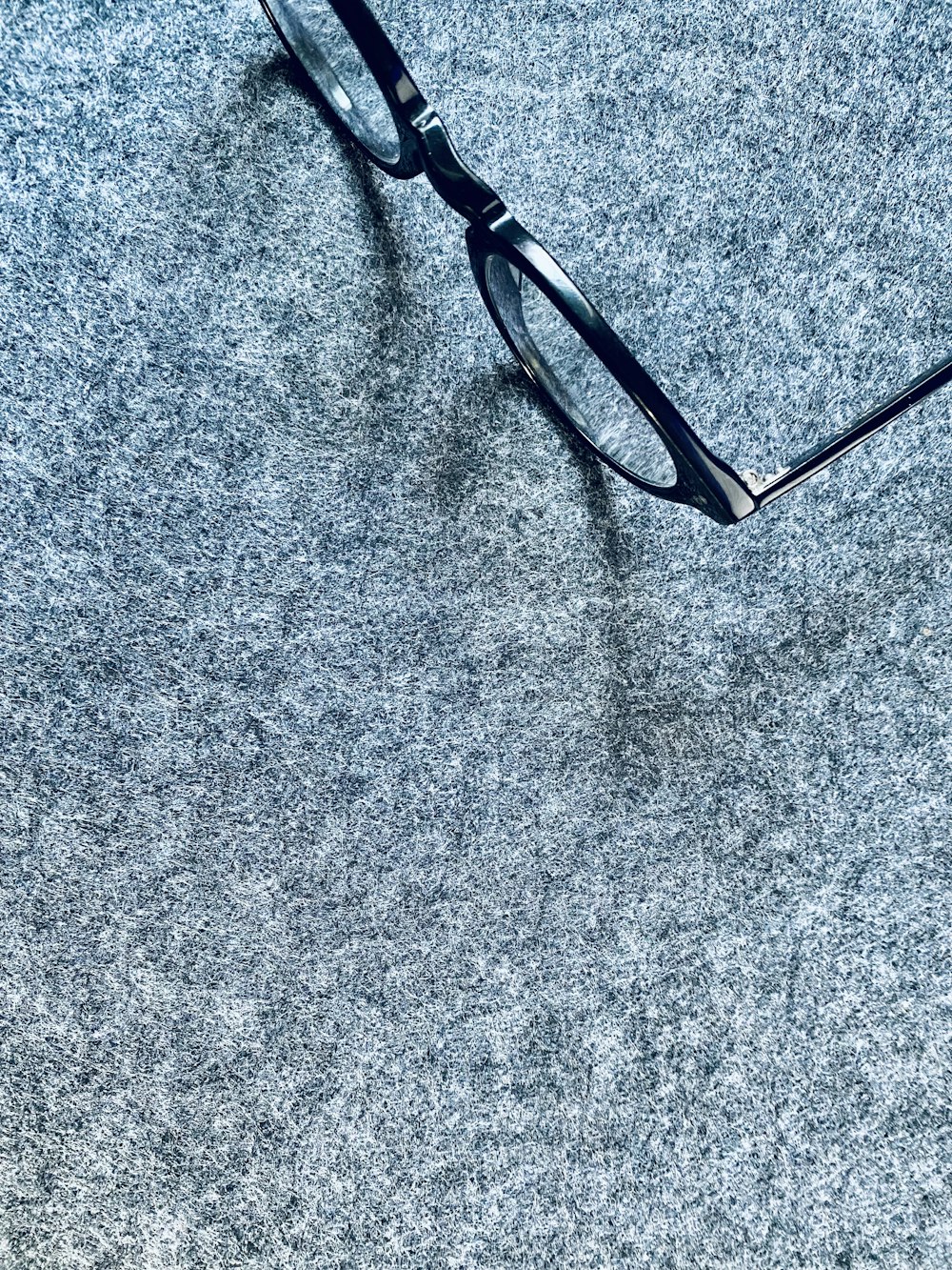a pair of glasses laying on top of a gray carpet