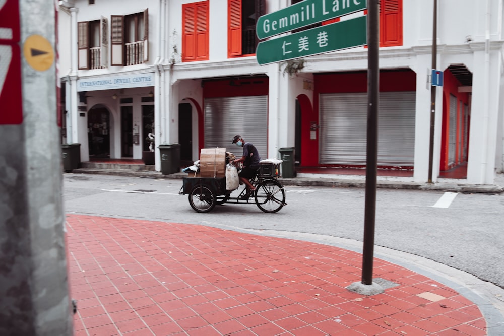 a man riding a cart down a street next to a tall building