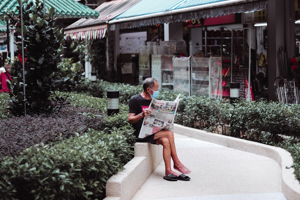 a woman sitting on a bench reading a newspaper