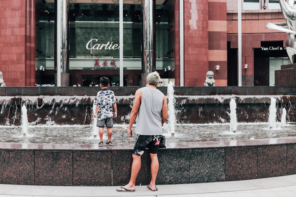 a man and a woman standing in front of a fountain