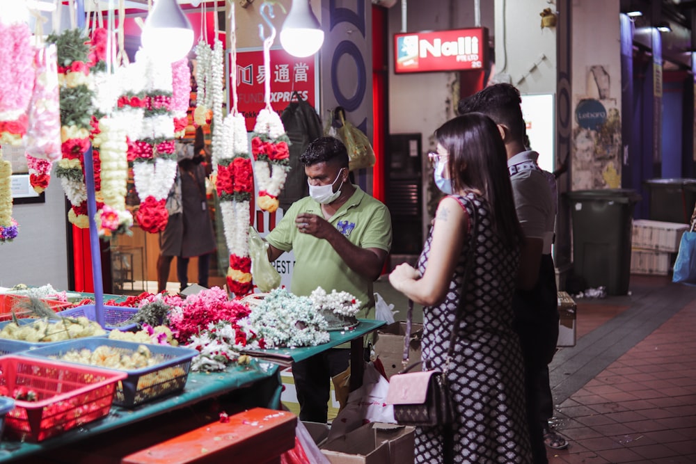 a man and woman standing in front of a flower shop