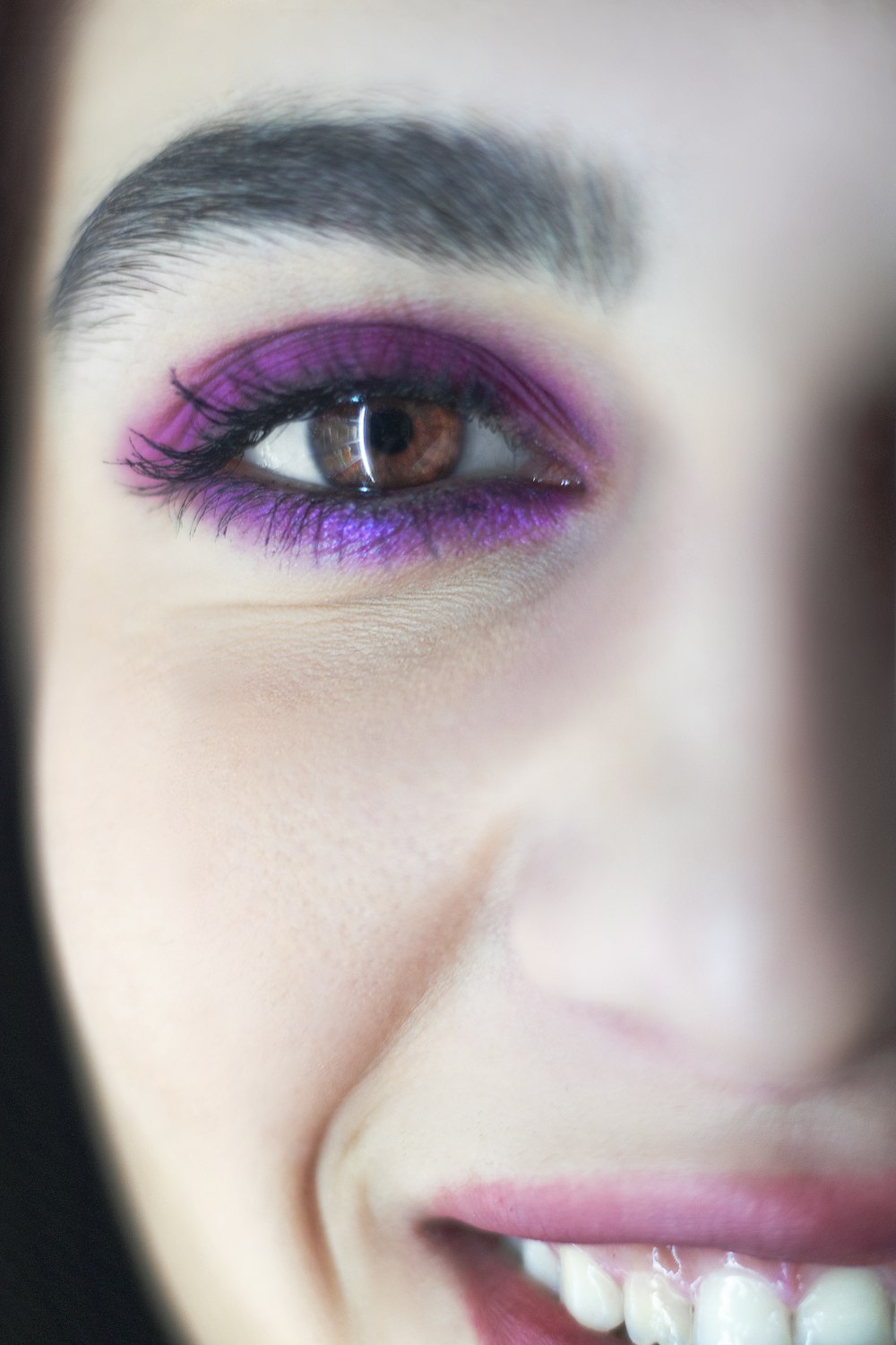 a close up of a woman's face with purple eye makeup