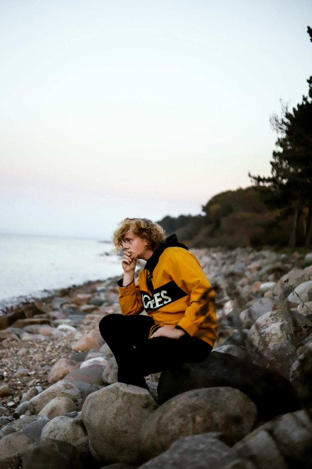 a person sitting on a rock by the water