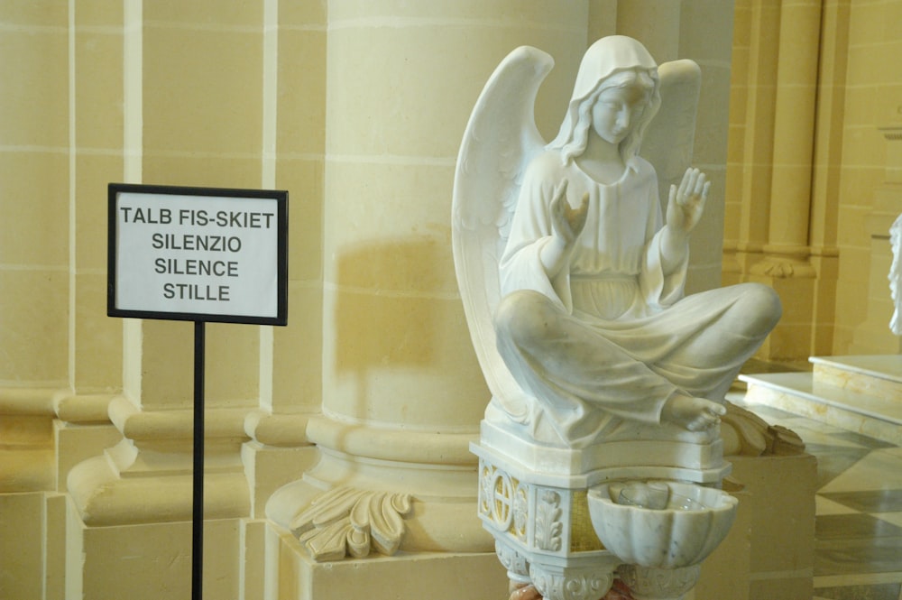 a statue of an angel with a sign in front of it