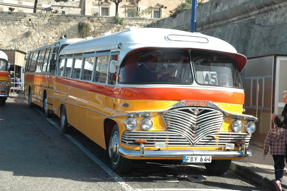 a yellow and orange bus parked next to a building