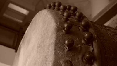 A close-up of a beautifully crafted Mandar drum resting on handmade paper with terracotta accents.