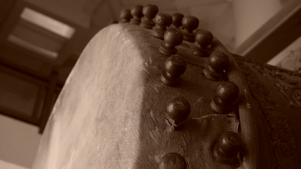Close-up of artisan hands shaping a Mandar drum with natural materials in a rustic workshop.
