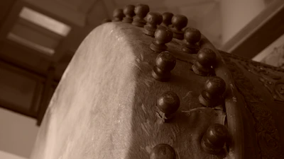 Close-up of a rustic wooden djembe drum with intricate carvings, set against a warm village backdrop.