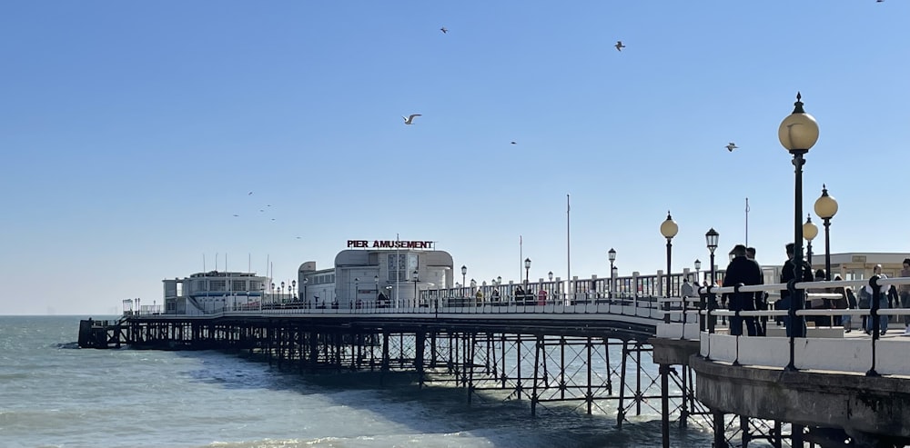 a pier with people standing on it next to the ocean