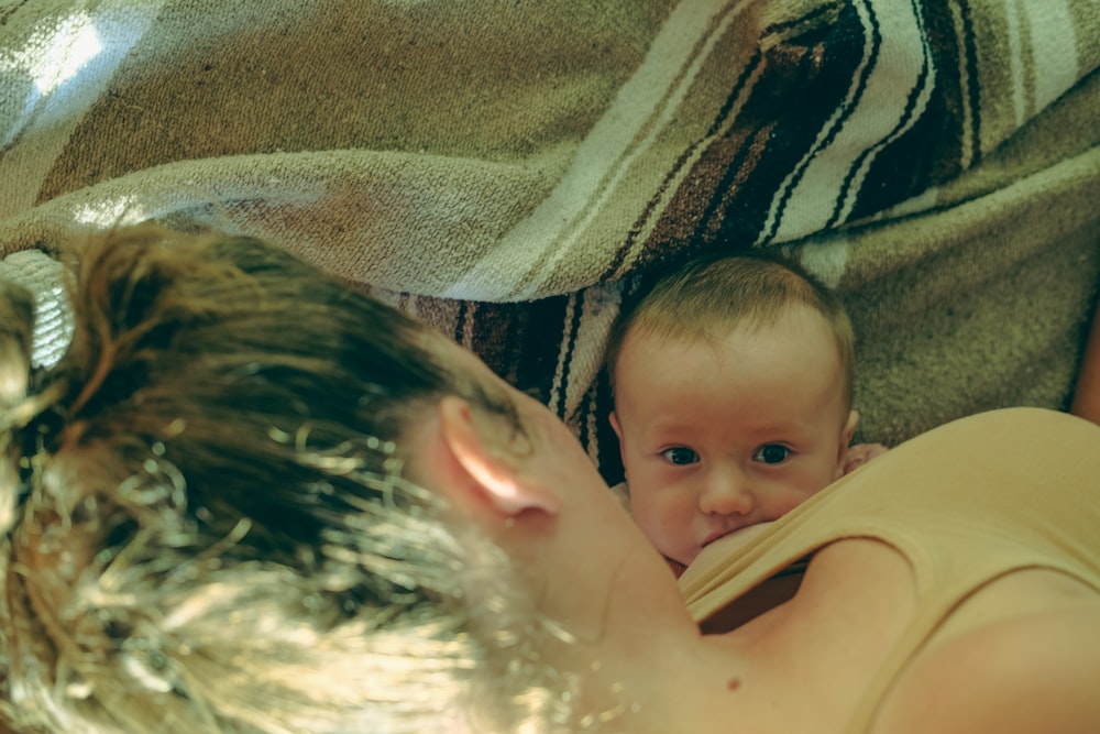 a woman holding a baby under a blanket