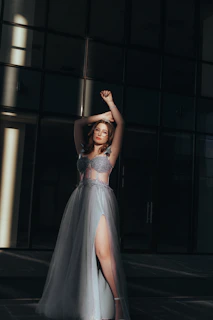 Evening gown with a soft, billowing bubble hem illuminated by warm spotlight in a dark room.